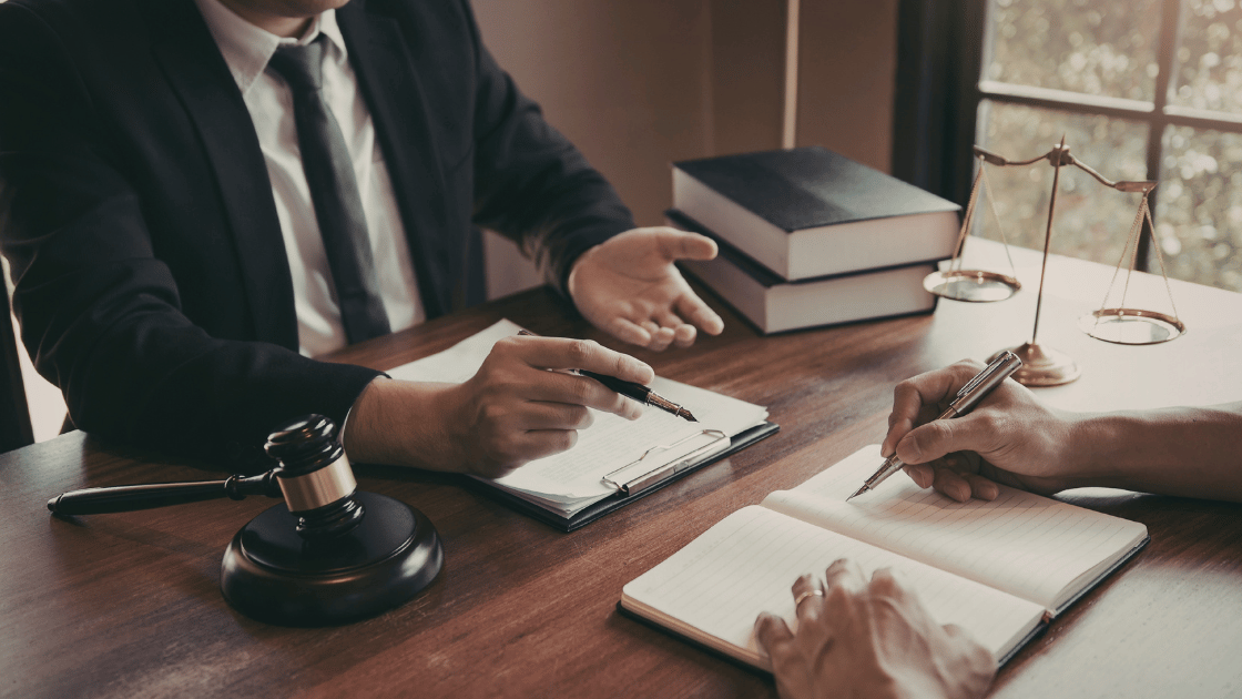 Two people sitting across from each other at a desk discussing business